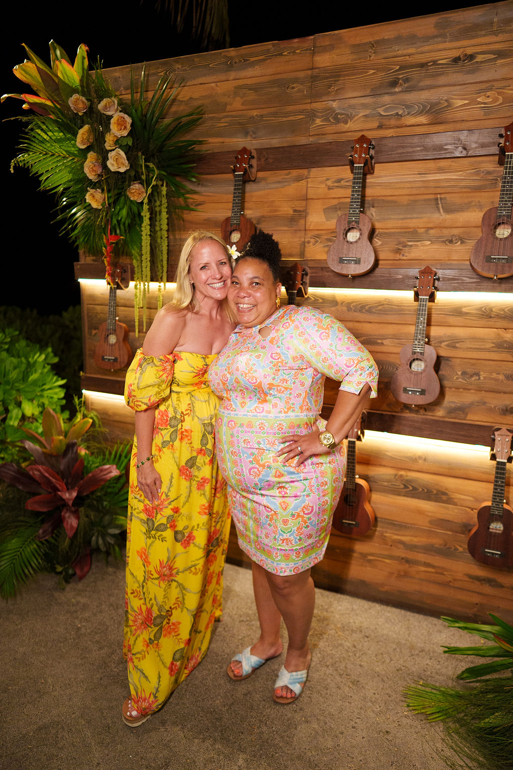 two women in hawaii in front of ukulele wall.